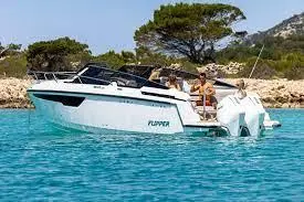 A sleek white boat named Flipper cruising on clear blue water with four people enjoying the sunny day in the background.